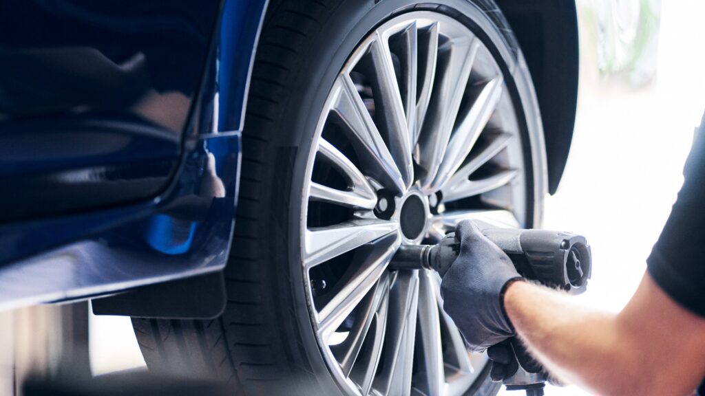 Mechaniker wechselt ein Autorad in einer Autowerkstatt mit einem pneumatischen Schraubenschlüssel