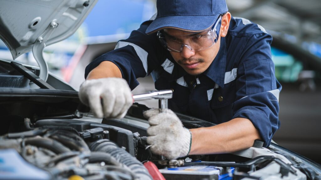 Porträt eines asiatischen Mechanikers, der die Sicherheit eines Autos überprüft. Wartung von beschädigten Teilen in der Werkstatt. Wartung und Reparatur. Konzept eines Reparaturdienstes.